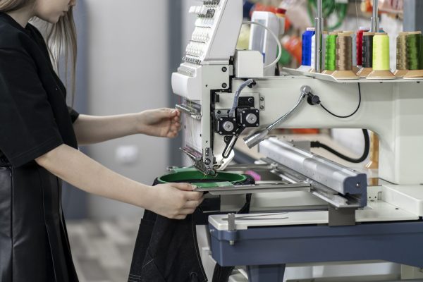 female worker using and  preparing automatic tailoring machine for work  on clothing manufature factory a female worker using and  preparing automatic tailoring machine for work  on clothing manufature factory